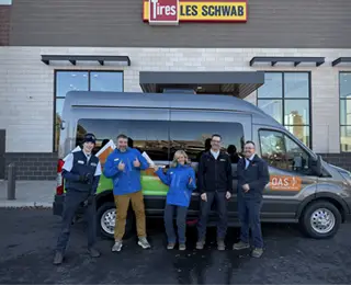 The Les Schwab and OAS teams stand in front of the OAS van with newly installed tires.