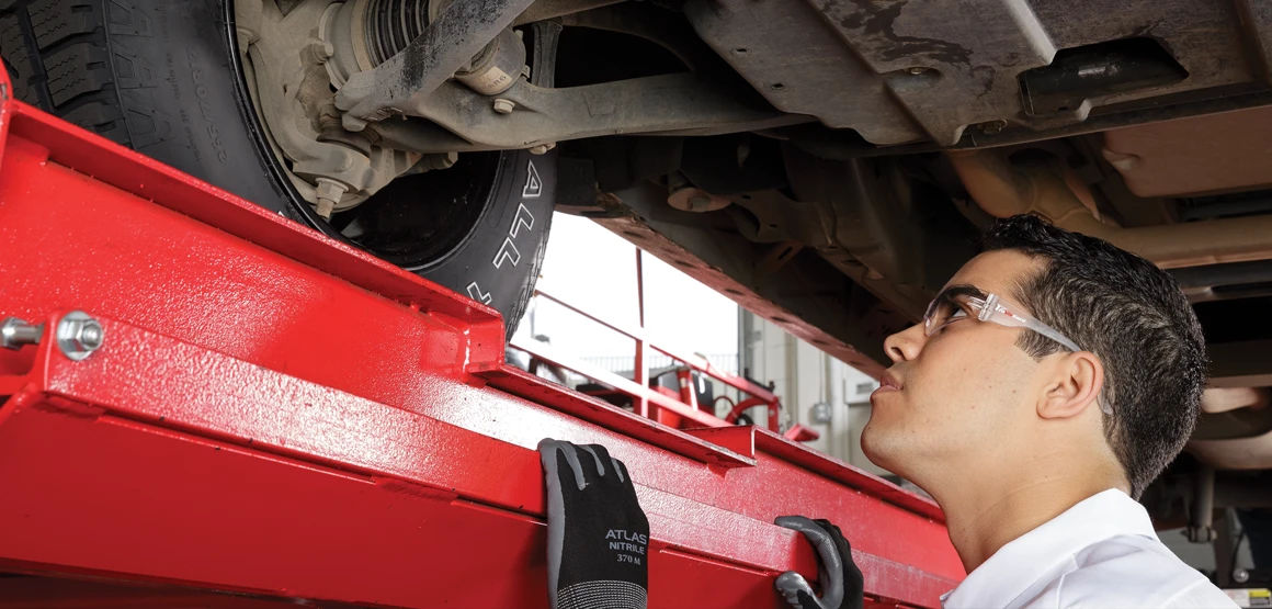 Les Schwab employee performing an inspection under a vehicle