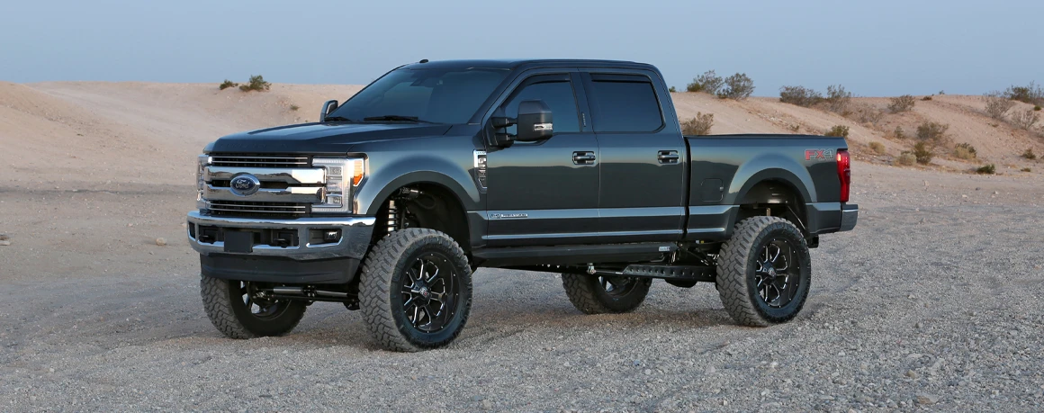 A lifted and leveled pickup truck parked just outside a desert landscape
