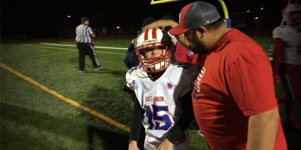 The East Union high school football coach pats a player on their head.