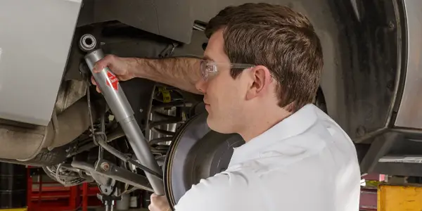 Les Schwab employee installing a new shock to a vehicle