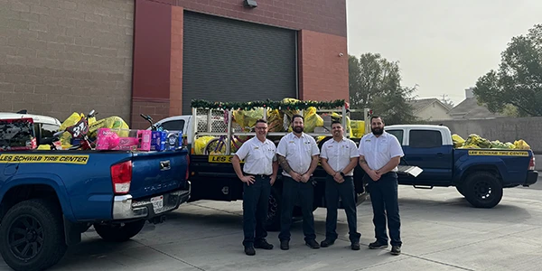Les Schwab managers in front of trucks loaded with toys