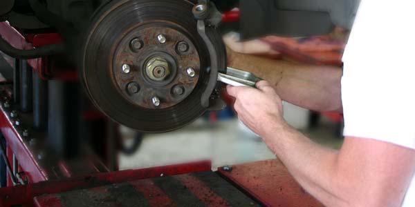 A Les Schwab technician working on a brake caliper.