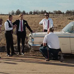 Les Schwab technician changing a tire on the side of a road